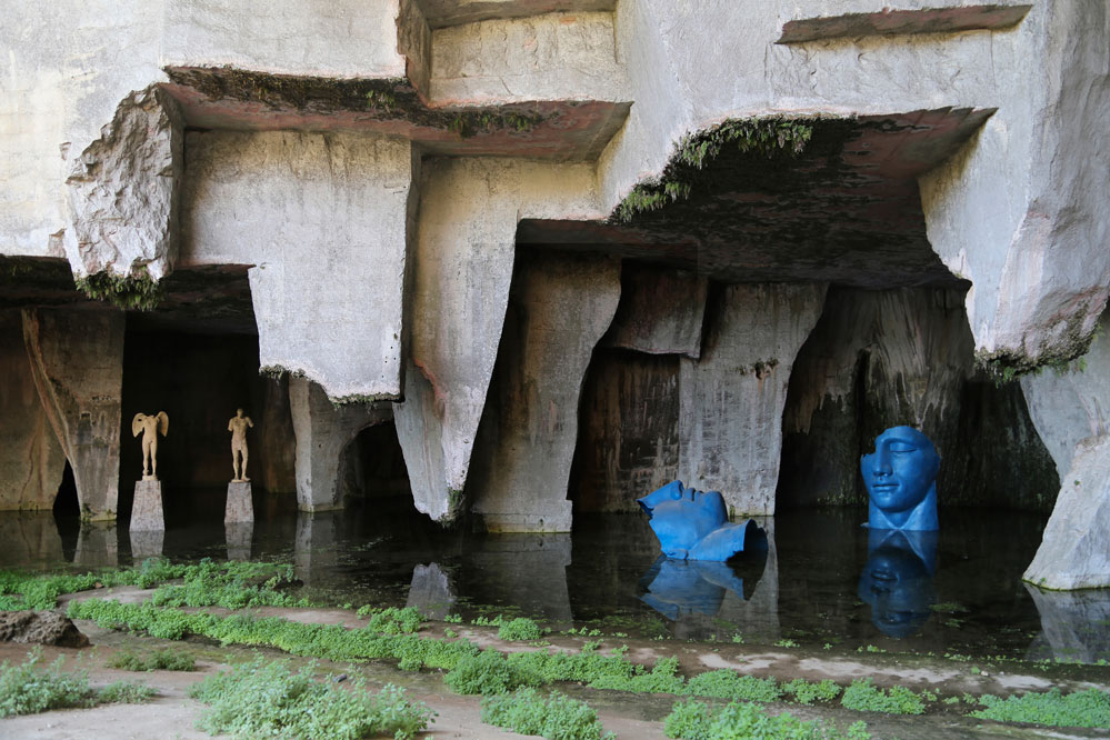 Sulla sinistra: Igor Mitoraj “Ikaria”, 1996, resina, 308x154x110 cm. Igor Mitoraj “Ikaro”, 1998, resina, 360x120x85 cm. Grotta dei Cordari Parco Archeologico Neapolis - Siracusa Sulla destra: Igor Mitoraj “Grande Sonno”, 2002, resina, 500x500x500 cm. Grotta dei Cordari Parco Archeologico Neapolis - Siracusa © Ph. Nicola Gnesi per Atelier Mitoraj